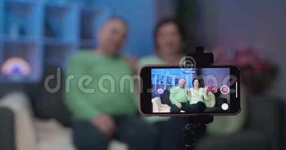 资深博主vloggers夫妇在家看着录相机的博客vlog友好的笑容成熟的老年人视频的预览图