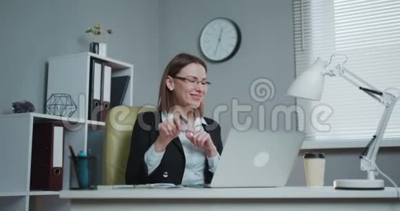 有创意的年轻女人坐在她的办公桌上美丽女商人一边跳舞的肖像视频的预览图