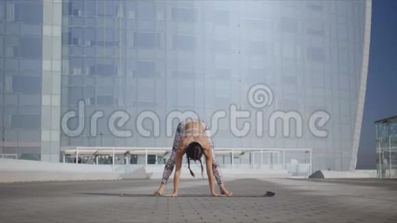 在城市街道上做瑜伽的女人在户外垫子上做花环姿势的女士视频的预览图