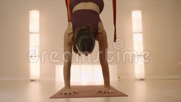 女人在空中瑜伽工作室练习瑜伽瑜伽教练站在垫子上双手站立视频的预览图