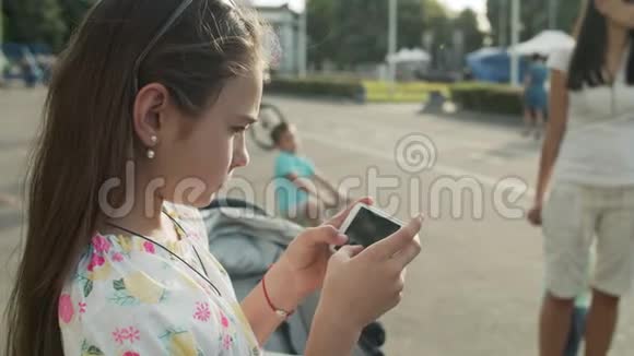 严肃的女孩在公园玩手机可爱的女孩在外面打电话视频的预览图