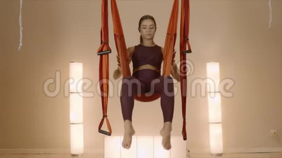 女孩倒挂在吊床上女士在吊床上摆倒鸽子姿势视频的预览图