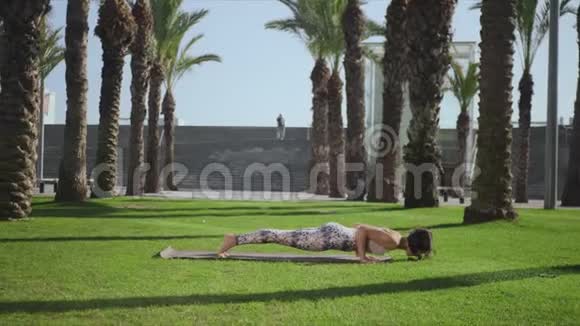 瑜伽教练在公园做眼镜蛇姿势女子在草地上练习瑜伽视频的预览图