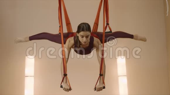 上课时在吊床上劈腿的女人女运动员练习反力瑜伽视频的预览图