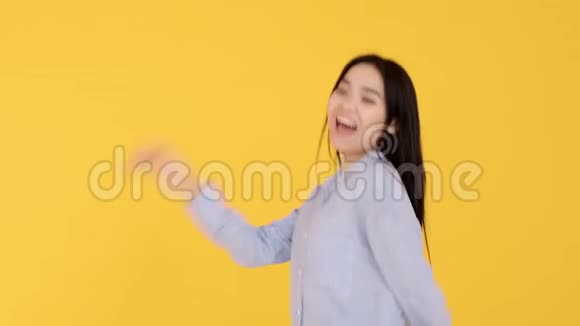 亚洲女孩在黄色背景下跳舞慢动作录像女人在玩相机视频的预览图