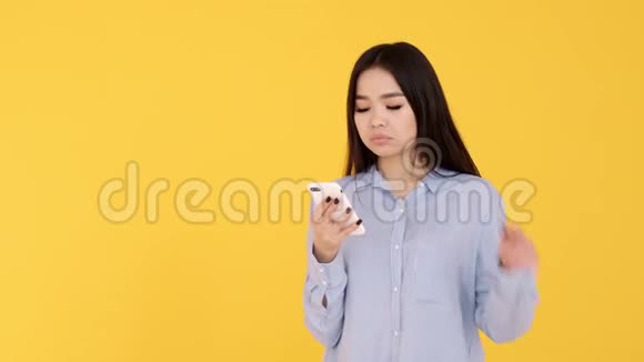 黄色背景的亚洲女孩通过电话收到消息的喜悦视频的预览图