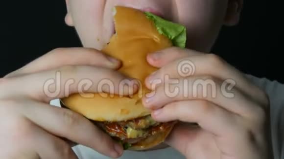 一个十几岁的男孩的嘴他吃了一个多汁的汉堡一个芝士汉堡或汉堡里面有奶酪肉切片和泡菜视频的预览图