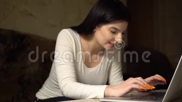 年轻的女人在笔记本电脑上聊天微笑着在家打字女孩用笔记本发短信视频的预览图