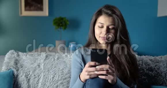 微笑女孩用手机在线聊天视频的预览图