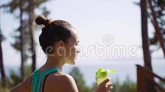 漂亮的女孩慢跑后从塑料瓶里喝水视频的预览图