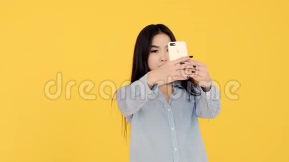 女孩自拍黄色背景亚裔女子通过电话欣赏她们视频的预览图