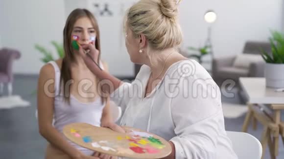 艺术家画在女孩脸上然后看着相机微笑身体艺术概念人体艺术作品视频的预览图