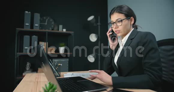 有魅力的女人用电话和笔记本电脑说话视频的预览图