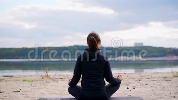 女人坐在沙滩上做瑜伽时正在冥想视频的预览图