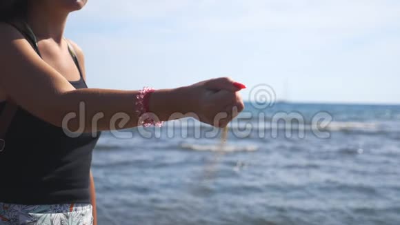 站在海边拿着一把沙子的不知名的年轻女子黄色干砂灌入母管视频的预览图