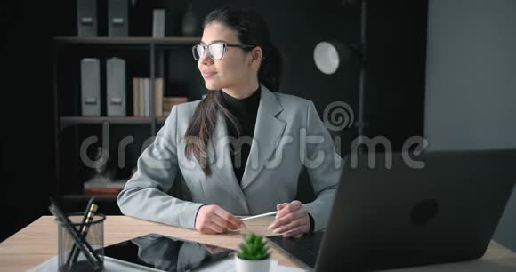 快乐的年轻女士坐在办公桌上手提电脑视频的预览图
