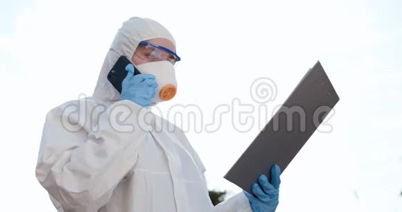 穿着化学防护服的女孩在打电话冠状病毒COVID19大流行自信的亚洲保护医生视频的预览图