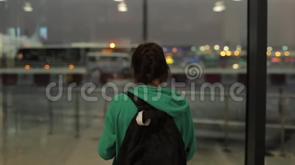 一个年轻的女孩一个晚上在飞机机场等待和拍照的女人后方视野视频的预览图