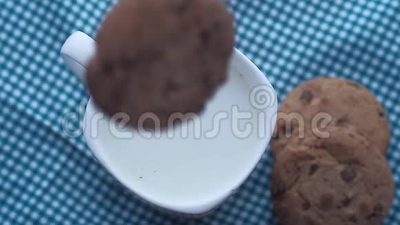 饼干滴在桌子上的牛奶杯里视频的预览图