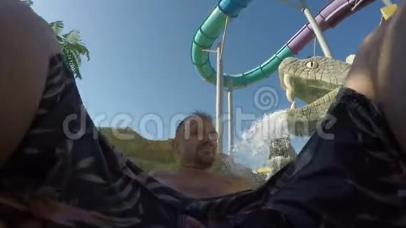 在水上公园的瀑布下漂浮着橡胶圈的白人关门视频的预览图