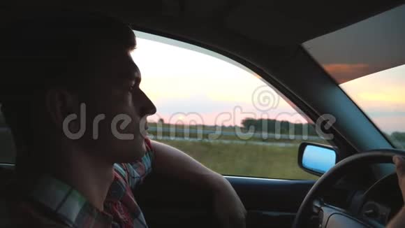 穿着衬衫开车穿过农村的帅哥的形象他的手从窗外伸出骑着车的年轻人视频的预览图