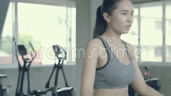 亚洲年轻女性在健身房跑步机上跑步锻炼亚洲女孩锻炼有氧运动累了擦汗视频的预览图