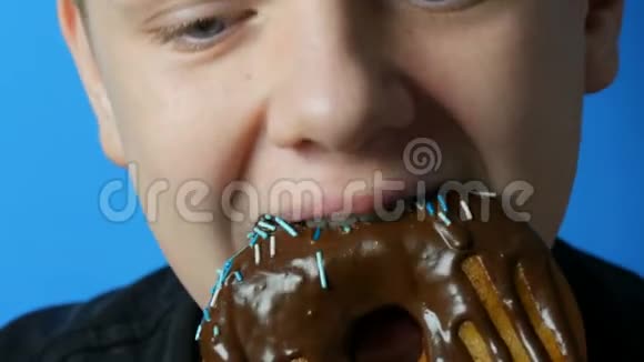 十几岁的男孩吃巧克力脂肪甜甜圈有害的甜食垃圾食品视频的预览图