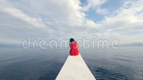一个悲伤的年轻女子独自坐在船边的后景视频的预览图