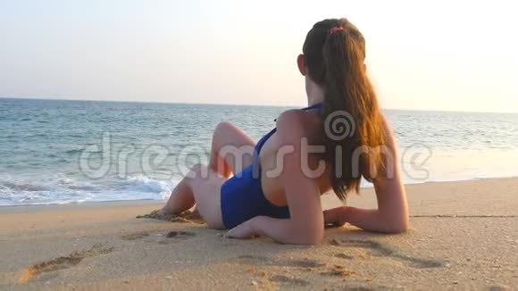 穿着泳衣躺在海边和日光浴的年轻女孩美丽的白种人女人在海边放松视频的预览图