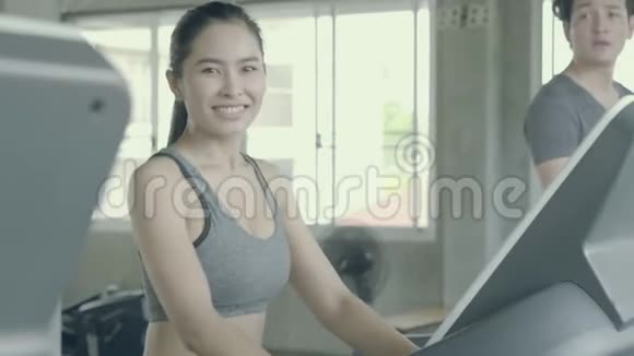 亚洲青年男子和妇女在运动健身房里用跑步机进行有氧运动训练视频的预览图