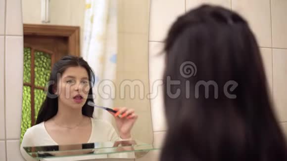 年轻女子刷牙牙膏浴室里的镜子口腔卫生视频的预览图