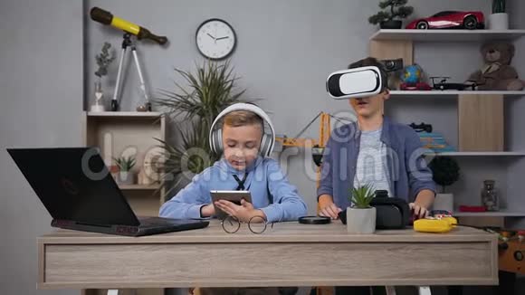 在游戏室使用虚拟现实护目镜和平板电脑享受休闲的满意青少年男孩的近景视频的预览图