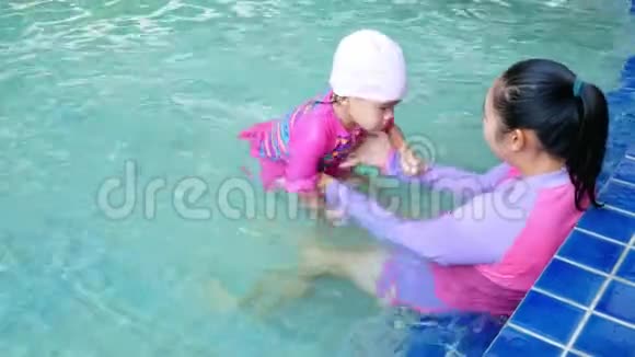 亚洲小女孩学游泳妈妈在暑假期间在游泳池里照顾孩子视频的预览图