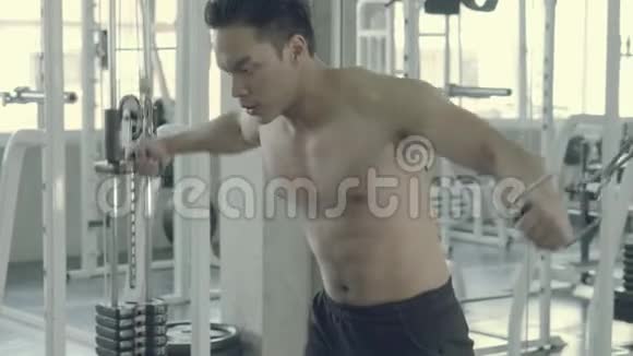 年轻的亚裔男子在健身房里做缆绳三头肌拉起来锻炼身体视频的预览图