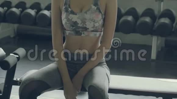 美丽的年轻亚洲女人在健身房锻炼后疲惫而疲惫亚洲女孩有汗水和擦拭休息休息时间视频的预览图