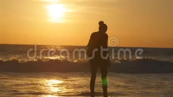 年轻的女游客带着背包在日落时沿着海边散步美丽的年轻旅人女人出海视频的预览图
