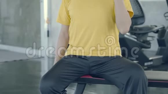 亚洲老人坐着举起哑铃训练手臂加强肌肉在健身房退休视频的预览图