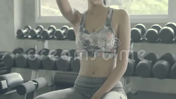 美丽的年轻亚洲女人在健身房锻炼后疲惫疲惫亚洲女孩有汗水和擦拭休息休息时间视频的预览图