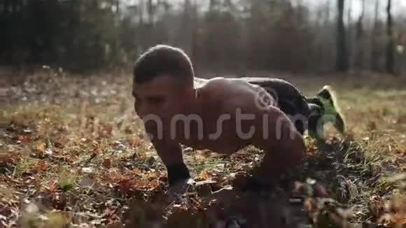 年轻的肌肉运动员在森林里做俯卧撑强壮的白种人赤裸的躯干视频的预览图