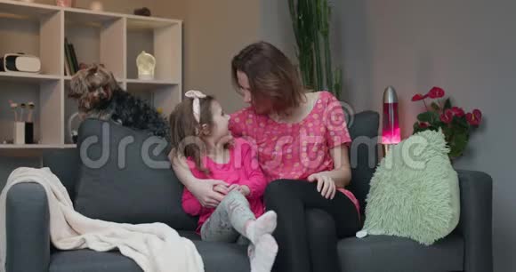 女人和她的小女儿坐在沙发上在电视上看喜剧电影笑着视频的预览图