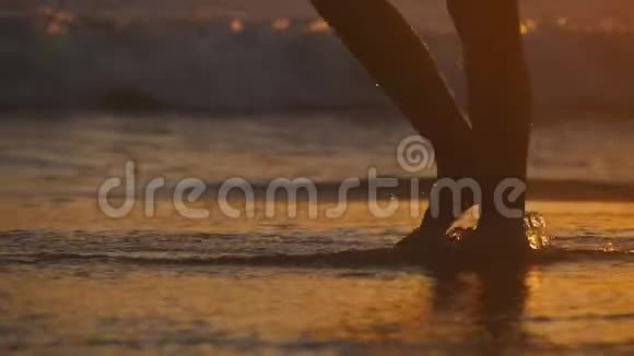 日落时分海浪拍打着赤脚走在岸边的女性双脚年轻女子沿着海边走的腿视频的预览图