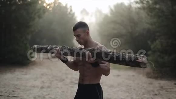 肌肉发达的白种人赤裸的躯干在森林里用原木做运动视频的预览图