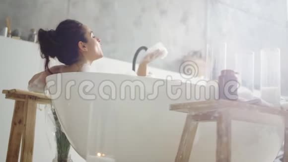 关闭性感女人吹泡沫微笑的女孩在洗澡时玩泡沫视频的预览图