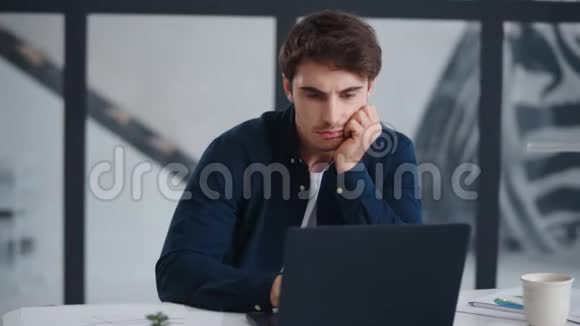 无聊的商人在办公室里看电脑屏幕干手提电脑的家伙视频的预览图