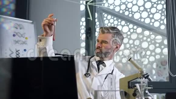 外观好看可敬的男医生穿着白色长袍用化学液体做实验视频的预览图