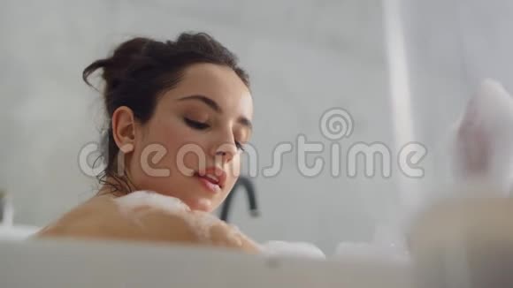 关闭性感女人吹泡沫浴缸慢动作视频的预览图