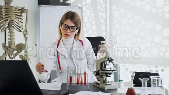 集中吸引力的女医务工作者在她的工作中写下标记与瓶填透明液体视频的预览图