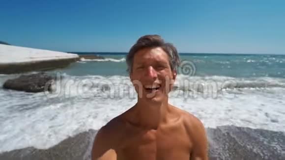 微笑运动员自拍站在海滩背景与波浪海视频的预览图