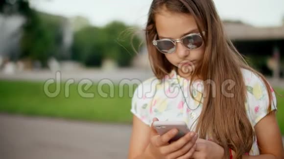 微笑的女孩在户外玩手机游戏站在公园里的女孩视频的预览图