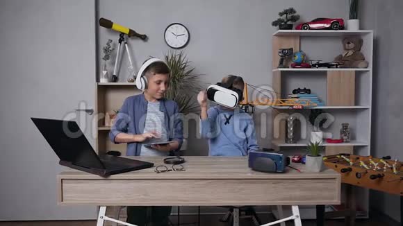 近距离观看微笑好看的1012岁男孩他们喜欢使用特殊的虚拟3D眼镜和平板电脑进行电子游戏视频的预览图